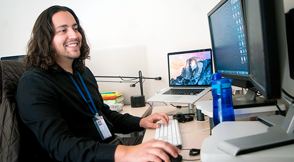 Male staffer smiling at desktop computer