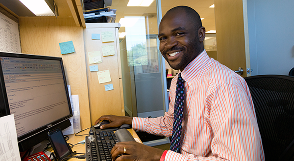 Young male staffer smiling while working at office computer