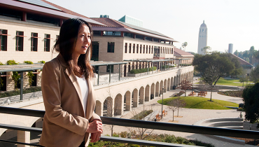 Asian female looking into distance on balcony, building behind to her left