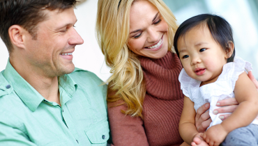 Happy young couple holding their Asian toddler daughter