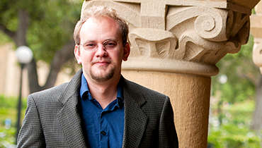 Portrait of staffer Christopher Bennett with Memorial Quad columns behind him