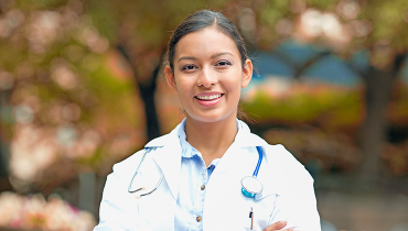 Female doctor in white lab coat with autumn foliage in background