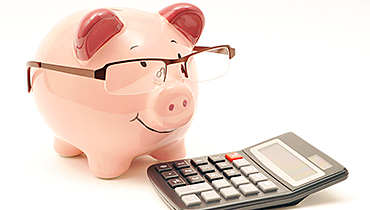 Piggy bank wearing glasses next to calculator