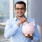 Young man putting money into piggy bank