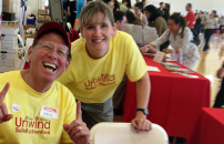 Male and female BeWell staffers at a Wellness Fair, distributing Tshirts and ecofriendly bags