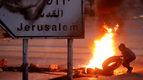 Un manifestant jette un pneu dans une barricade en feu, près de la ville de Ramallah, en Cisjordanie.