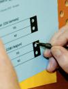 man marks choices on voting ballot