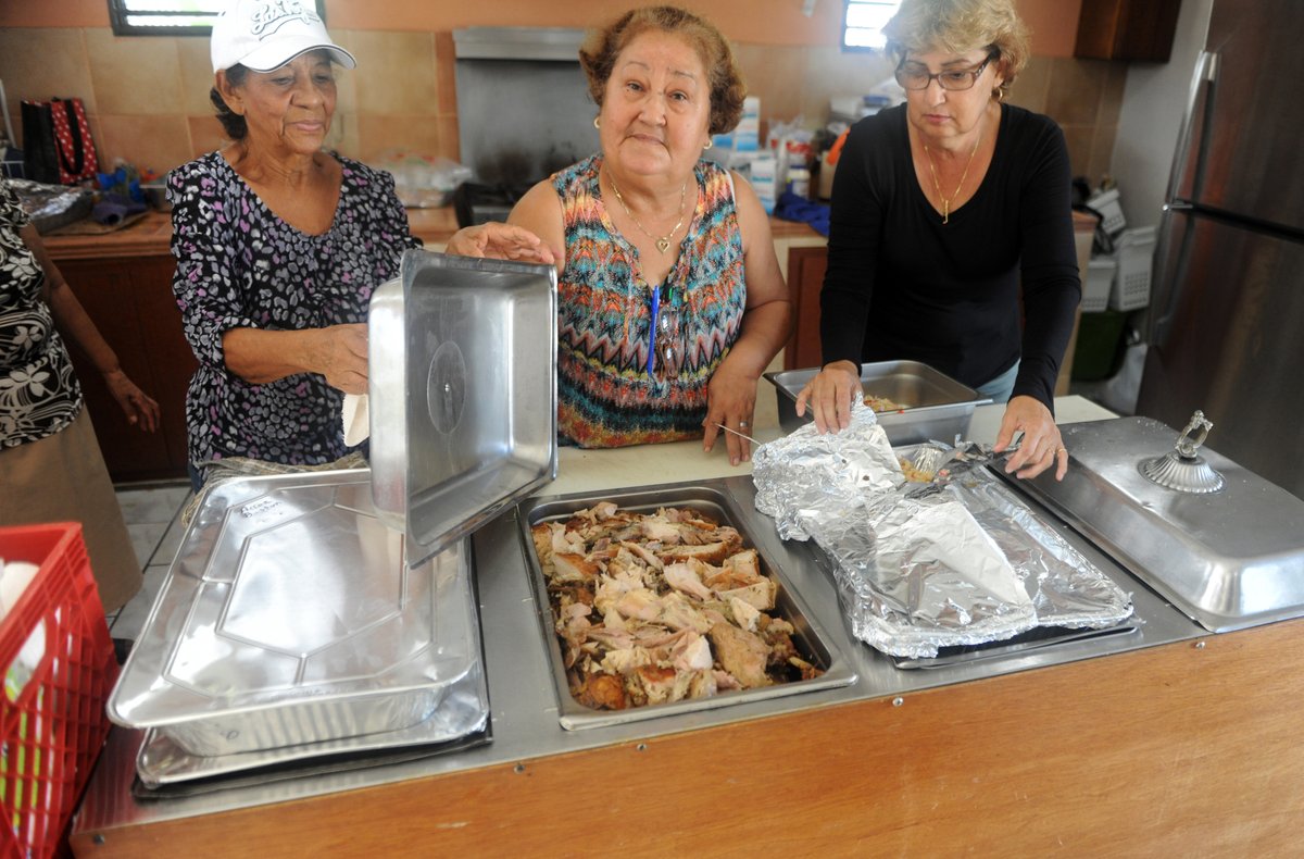 Ana Luis Vazquez, Dalila Gonzalez, and Mary Rolon show off a tray of roasted turkey inside the kitchen at the Centro de Bendicion on Nov. 22. Serving those in need within a San Juan neighborhood hard hit by Hurricane Maria, around 30 volunteers presented a free traditional Puerto Rican holiday meal of turkey, fruit, macaroni salad, and rice and beans to more than 60 patrons on the day before Thanksgiving.