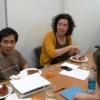 Students around a table eating pizza, talking, smiling