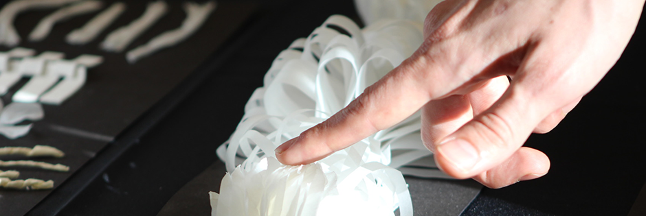 A hand touching paper artwork.