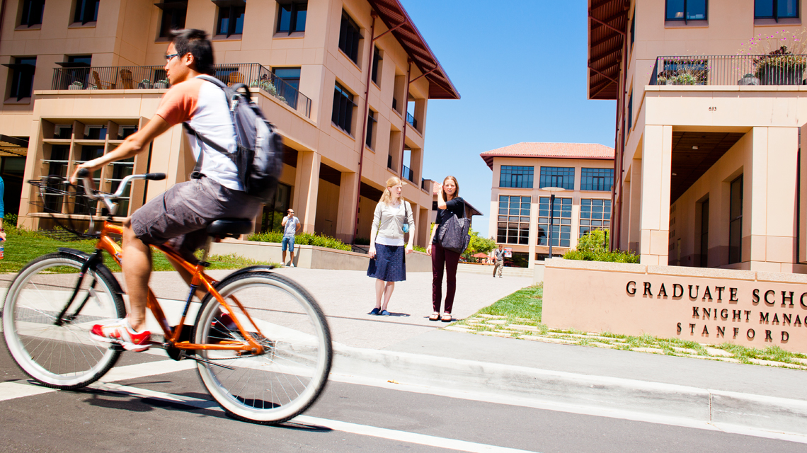 Students waiting to cross the street, bicyclist going by