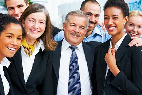 Women and men gathered together in professional attire smiling at the camera