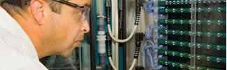 image of male scientist with safety glasses looking closely at scientific equipment