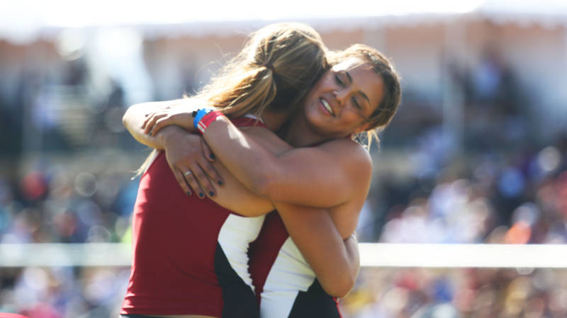 Rebecca Hammar (r.) gets a hug from Valarie Allman after they placed 3-4 in the discus. Photo by David Kiefer.