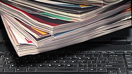 A stack of magazines laying on a computer keyboard