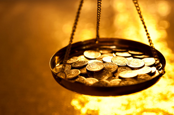 Image of a scale with coins surrounded by fire