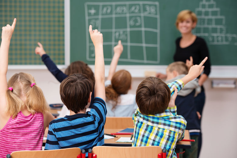 kids raising their hands in math class / racorn/Shutterstock
