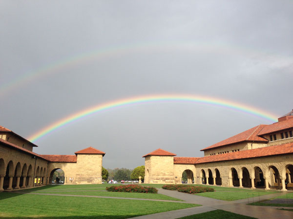 Photo of Stanford's Main Quad shot from Memorial Court. There is a double rainbow over the Quad.