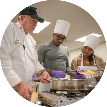 David Iott teaching two students in the Teaching Kitchen