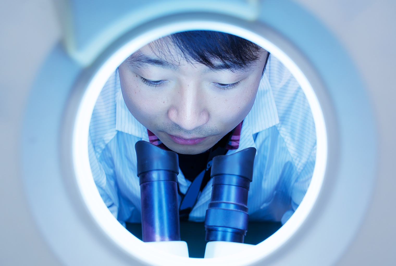 A scientist looking through a microscope shows application of chemistry.