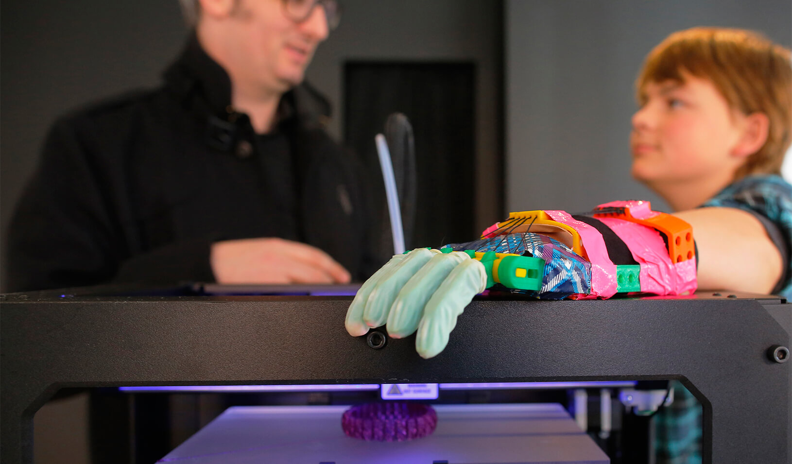 Empathy leads to better product design. Here, Twelve-year-old Leon McCarthy (R) rests his prosthetic hand on a MarkerBot Replicator 2 Desktop 3D Printer. His hand is made from parts made from a MakerBot 3D printer. | Reuters/Brian Snyder