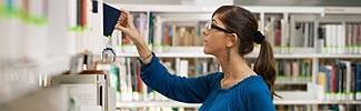 Woman looking at libraby shelf searching for additional information 