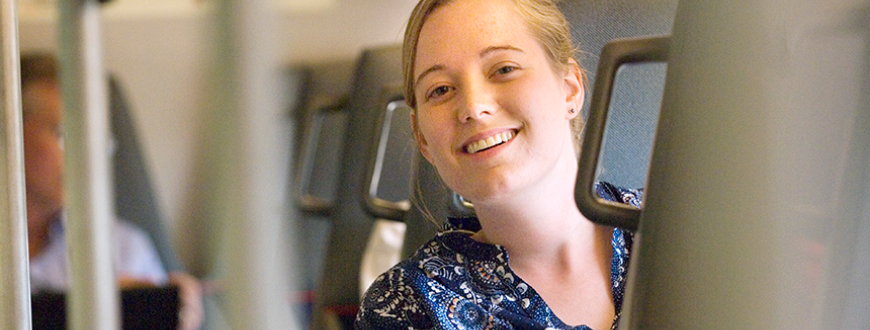 Young female staffer smiling while sitting in commuter train.
