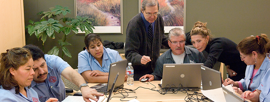 Male and female instructor teaching computer literacy class to men and women