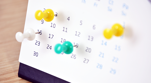 Desk calendar with colorful pushpins marking different dates