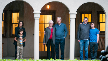 Retired emerita faculty member with husband, children and grandchildren standing in archways
