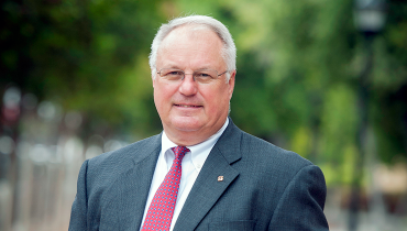 Portrait of Caucasian male staffer David Voss outside, with green foliage in background