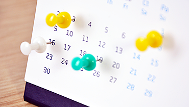 Desk calendar with colorful pushpins on different dates