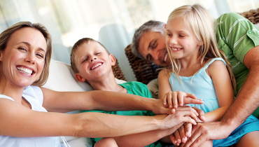 Happy young family of mother, father, son and daughter joining hands