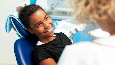 African American girl smiling at dentist while sitting in patient chair