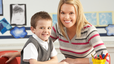Young female tutor with young boy in classroom