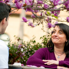 Young male talking to older female employee outside with fuschia blossoms in background