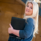 Female staff member holding black binder or padfolio in arm