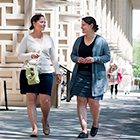 Two female employees walking outside the Alway building at the School of Medicine