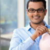 Young man wearing glasses with money in piggy bank