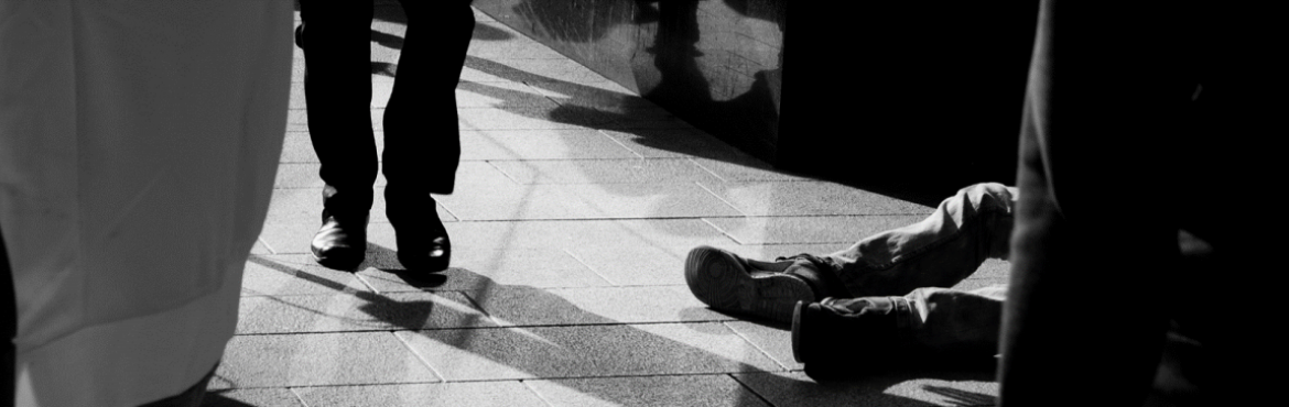 a man lies on the ground in a public area while others walk past him