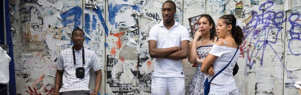 young adults standing in front of a wall with graffiti looking watchful