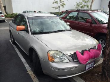 car with pink fabric mustache indicating the driver works for lyft, the ride-sharing company