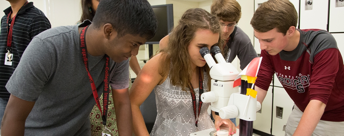 Three young students looking at a microscope during a summer conference. The Best Stanford Summer. Making a big splash–Summer Conferences at Stanford. Click to learn more.