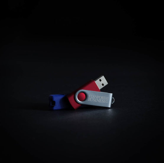 Flash drives including one with "Stanford Business" logo