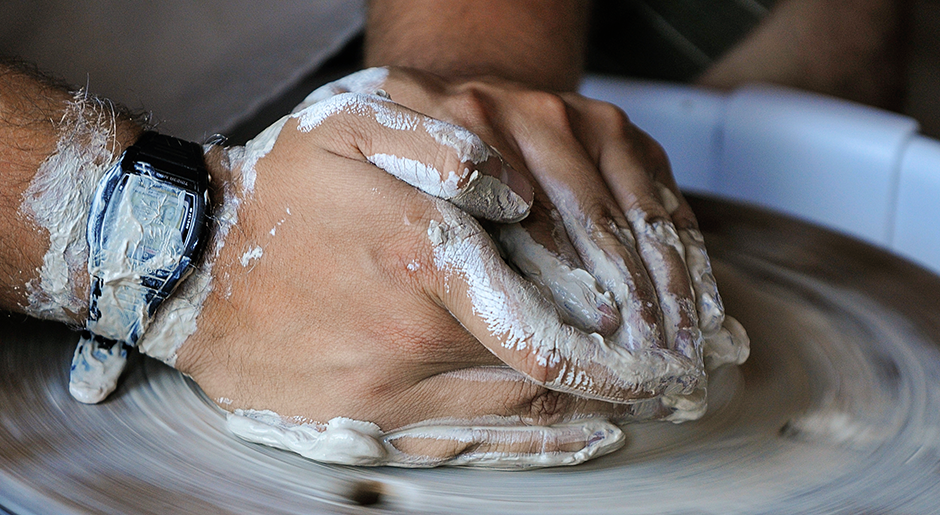 Clay-covered hands on a pottery wheel. Photo by Rod Searcey.