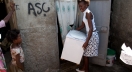 A woman moves Stanford-designed portable toilet into her home in Cap-Haitien, Haiti