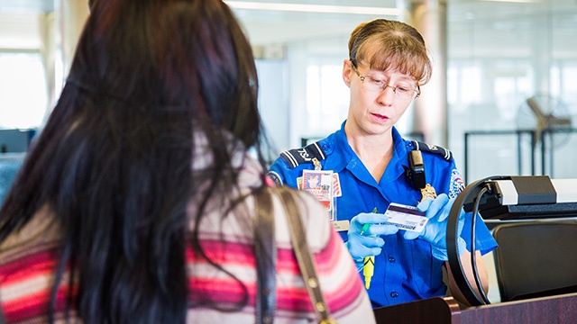 TSA Agent looking at a traveler's driver's license.