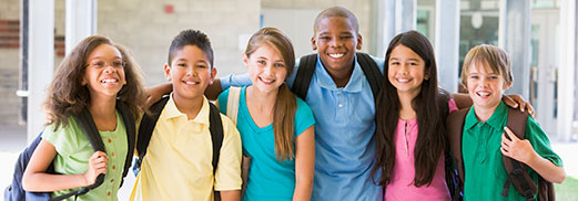 A group of young students and an adult look at a book on a field trip.