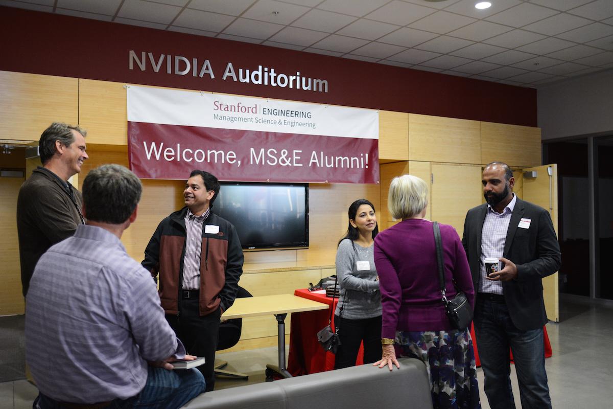 Attendees indulge in engaging conversation near the MS&E welcome banner.