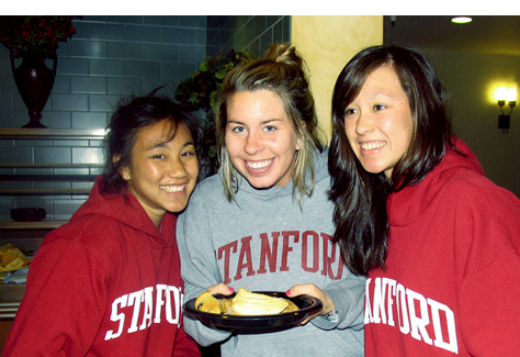 Three students with a plate of food in the dining hall